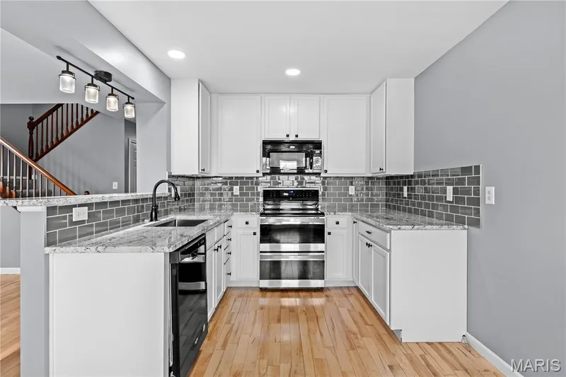 The updated Kitchen features granite counters, beautiful backsplash, stainless steel & black appliances & stunning white cabinets! — 819 Country Field Drive, Lake St. Louis, MO 63367