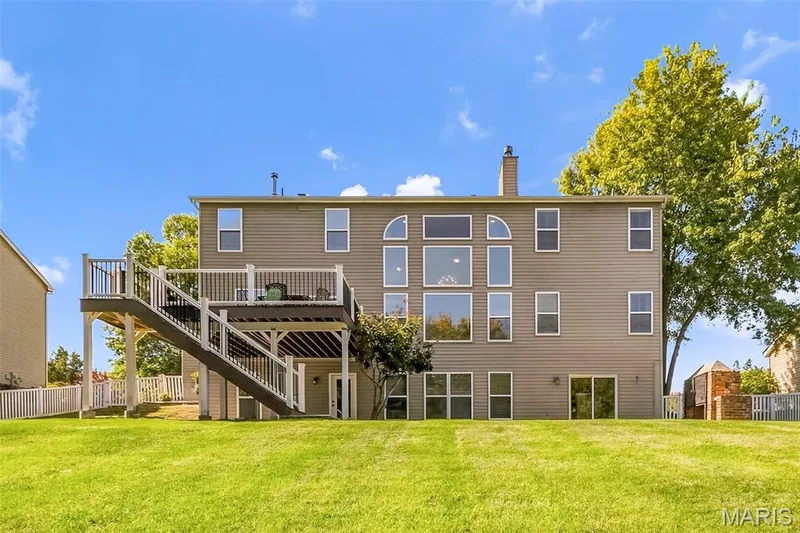 Back of home showcasing deck, patio underneath w/single door access, as well as 2nd patio outside of sliding glass doors. — 106 Crimson Oaks Court, Lake St. Louis, MO 63367