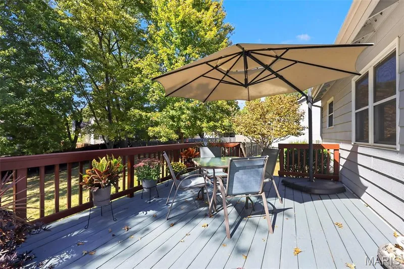 Elevated wooden deck featuring a stained railing, horizontal siding exterior, and mature surrounding trees — 120 Oak Valley Drive, St Peters, MO 63376