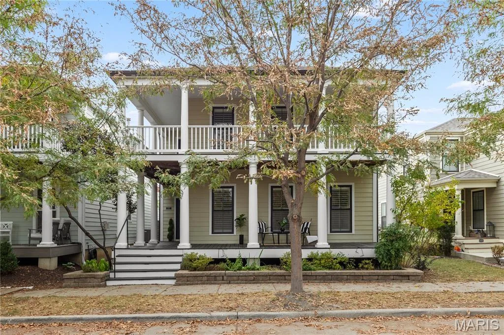 Two-story residence featuring horizontal lap siding, a covered ground-level porch, and an upper-level balcony supported by classic columns with a white railing — 3222 Starkville Street, St Charles, MO 63301