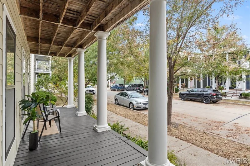 Covered front porch featuring dark-painted wood decking, exposed rafter ceiling, and structural columns with decorative capitals — 3222 Starkville Street, St Charles, MO 63301