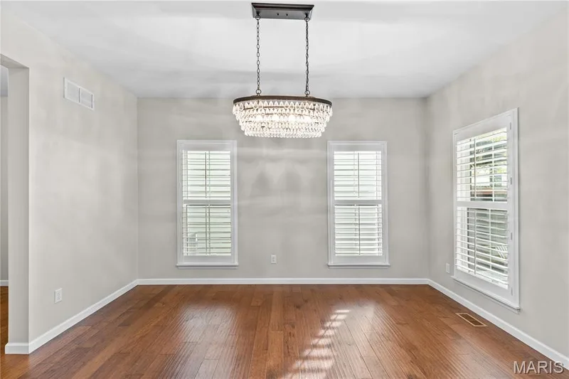 Hardwood flooring, crystal-accented chandelier, and multiple windows featuring integrated plantation shutters — 3222 Starkville Street, St Charles, MO 63301
