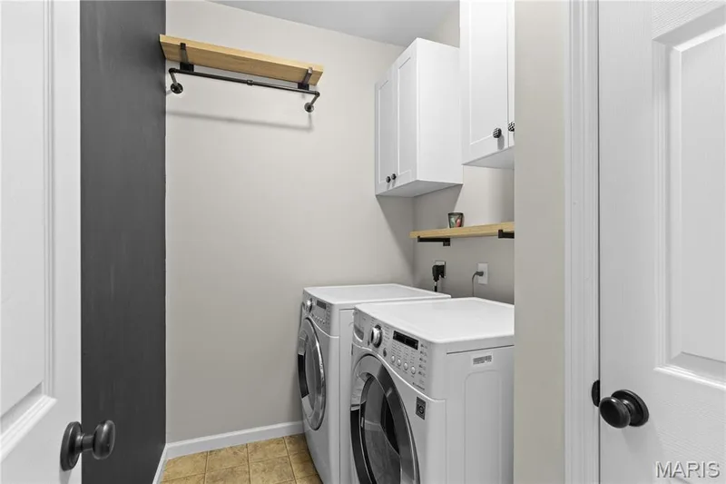 Laundry space featuring white shaker-style wall cabinetry, open wood-finish shelving, and industrial-style metal clothing rods — 3222 Starkville Street, St Charles, MO 63301