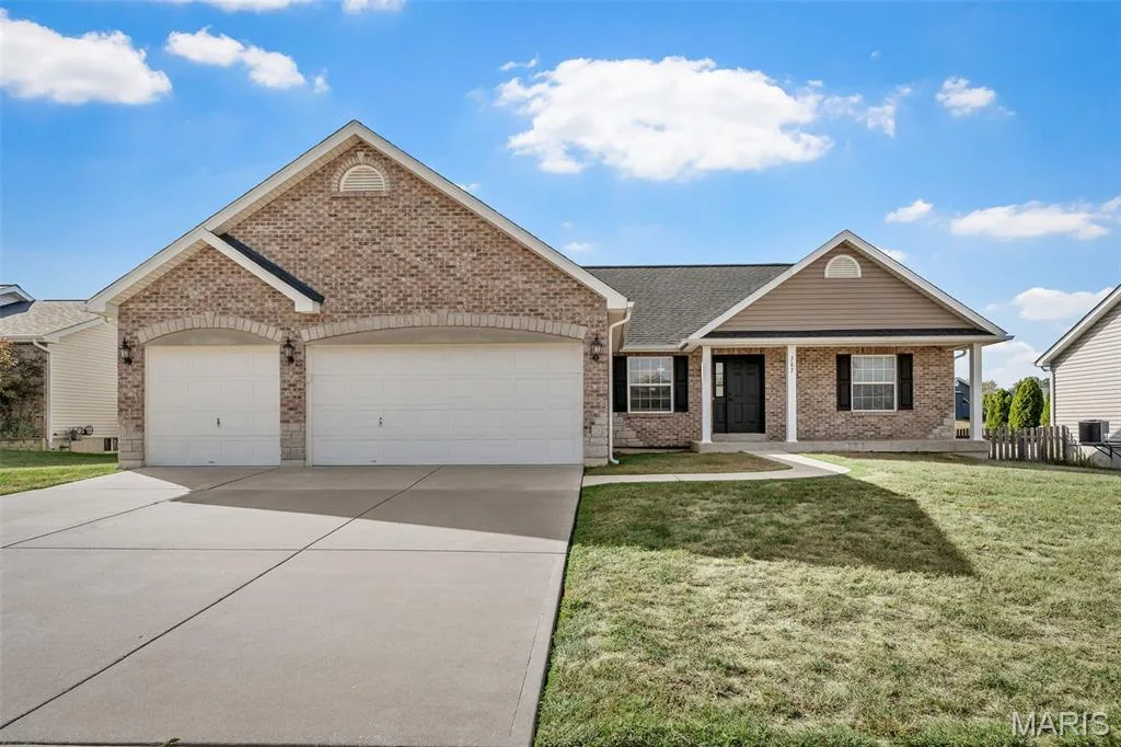 Single-story residence featuring a brick and horizontal siding exterior, arched garage entryways, a concrete driveway, and an covered front porch — 757 Lost Canyon Boulevard, Wentzville, MO 63385