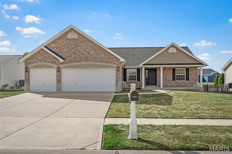 Brick and vinyl siding exterior featuring a covered front entry, three-car garage with arched brick detailing, and a concrete driveway — 757 Lost Canyon Boulevard, Wentzville, MO 63385