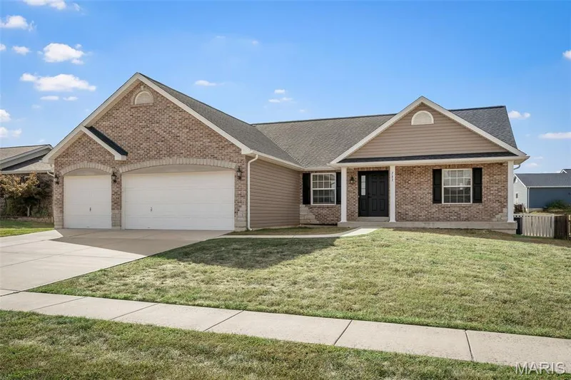 Exterior featuring a combination brick and horizontal siding façade, a three-car garage with arched architectural detailing, a covered front entryway, and double-pane windows with shutters — 757 Lost Canyon Boulevard, Wentzville, MO 63385
