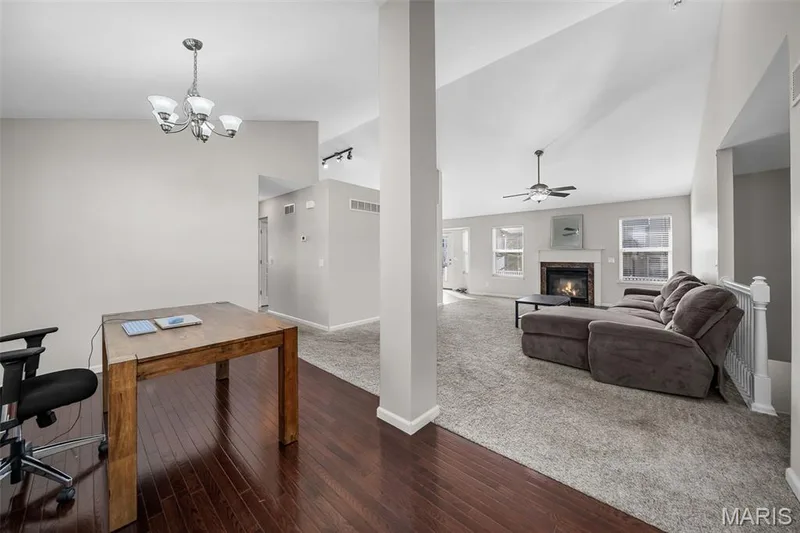Vaulted ceilings, dark wood-finish flooring, a fireplace with white mantle, ceiling fan, and chandelier lighting — 757 Lost Canyon Boulevard, Wentzville, MO 63385
