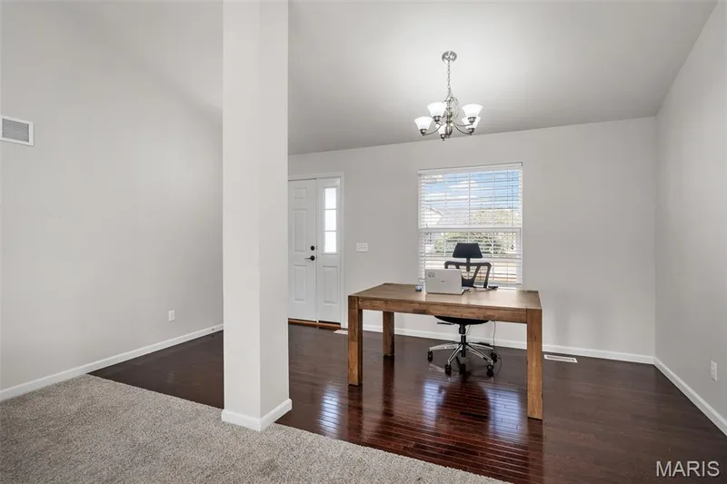 Interior space featuring dark-toned wood-finish flooring, neutral wall paint, a multi-arm chandelier, and a white paneled front door with side glass detailing — 757 Lost Canyon Boulevard, Wentzville, MO 63385