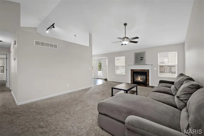 Vaulted ceilings with recessed lighting, carpeted flooring, and a fireplace featuring a stone-tile surround and white mantle — 757 Lost Canyon Boulevard, Wentzville, MO 63385
