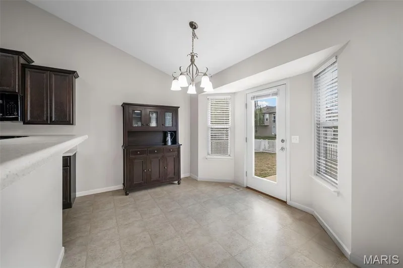 Breakfast area with bay window configuration, multi-light chandelier, and glass-paneled exterior door with neutral-toned vinyl flooring — 757 Lost Canyon Boulevard, Wentzville, MO 63385