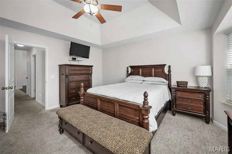 Bedroom featuring a tray ceiling, wall-to-wall carpeting, and a ceiling fan with light fixture — 757 Lost Canyon Boulevard, Wentzville, MO 63385