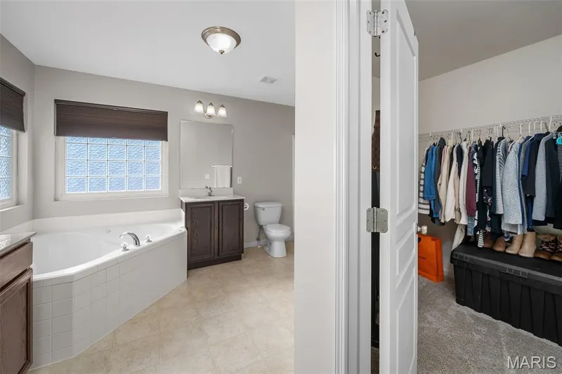 Master Bathroom Ensuite featuring a tile-surround soaking tub, glass block window, dark wood vanity — 757 Lost Canyon Boulevard, Wentzville, MO 63385