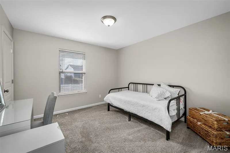 Neutral-toned interior space featuring neutral wall paint, wall-to-wall carpeting, a window with horizontal blinds, and a central ceiling-mounted light fixture — 757 Lost Canyon Boulevard, Wentzville, MO 63385