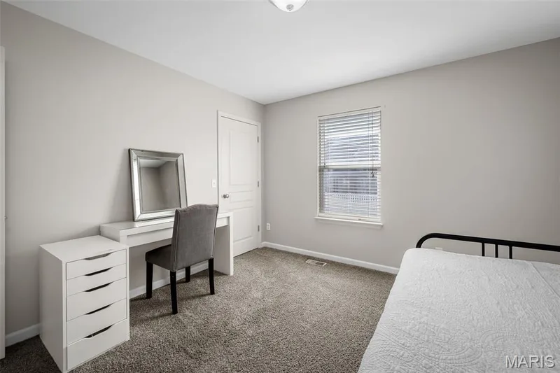 Neutral-toned interior featuring wall-to-wall carpeting, a single-panel interior door, a dual-pane window with blinds, and a flush-mount light fixture — 757 Lost Canyon Boulevard, Wentzville, MO 63385