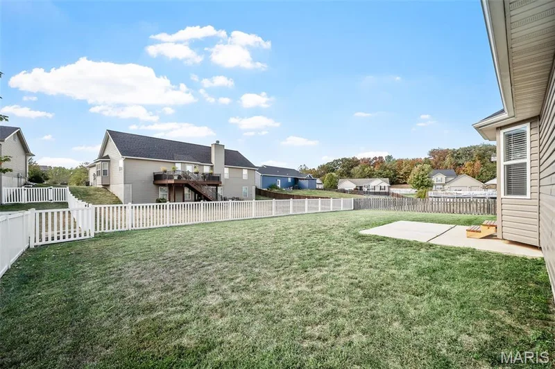 Fenced backyard featuring a manicured lawn, concrete patio, and vinyl perimeter fencing — 757 Lost Canyon Boulevard, Wentzville, MO 63385