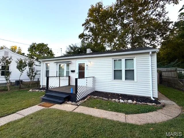 Single-story exterior featuring light-colored horizontal siding, a raised wood-finish deck with lattice detailing, and concrete pathways — 529 Emmons Avenue, St Charles, MO 63301