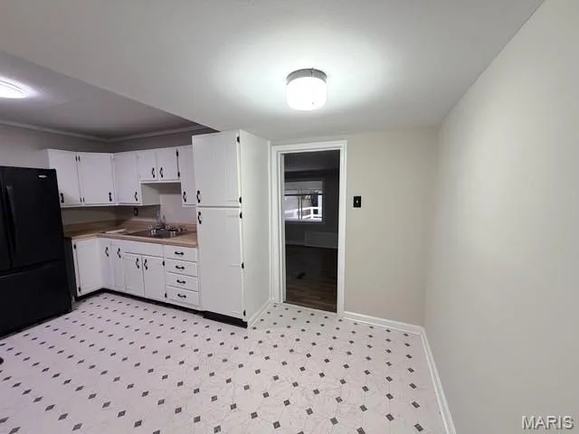 Kitchen featuring white cabinetry, wood-finish countertops, stainless steel dual-basin sink, and patterned vinyl flooring — 529 Emmons Avenue, St Charles, MO 63301