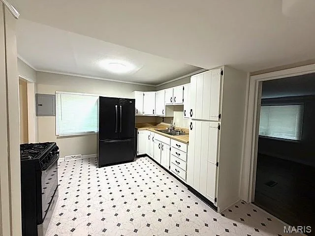 Kitchen featuring white cabinetry, black appliances, a double-basin stainless steel sink, and patterned flooring — 529 Emmons Avenue, St Charles, MO 63301