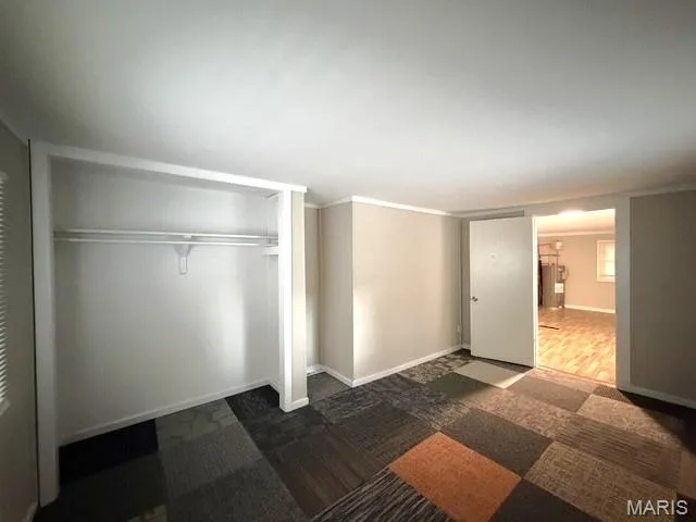 Interior space featuring multi-tonal modular carpet tiles, a built-in reach-in closet with integrated shelving, and a neutral wall finish — 529 Emmons Avenue, St Charles, MO 63301