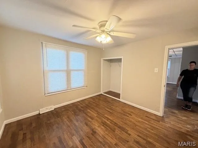 Interior space featuring wood-finish flooring, a multi-blade ceiling fan with integrated lighting, and a recessed closet with shelving — 529 Emmons Avenue, St Charles, MO 63301