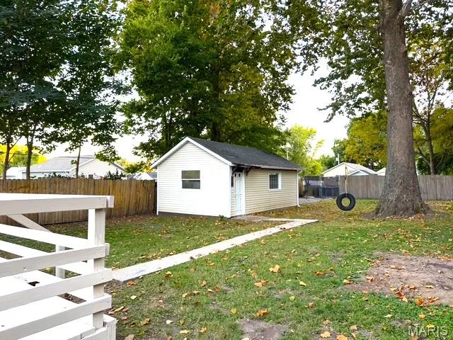 Backyard featuring a white detached outbuilding, wood-slat perimeter fencing, and a paved walkway — 529 Emmons Avenue, St Charles, MO 63301