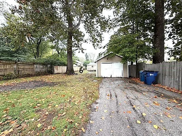 Backyard area featuring a detached garage, asphalt driveway, and wood-panel perimeter fencing — 529 Emmons Avenue, St Charles, MO 63301