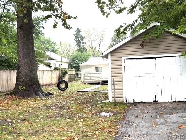 Detached garage with horizontal siding, paved driveway, enclosed backyard, and mature tree — 529 Emmons Avenue, St Charles, MO 63301