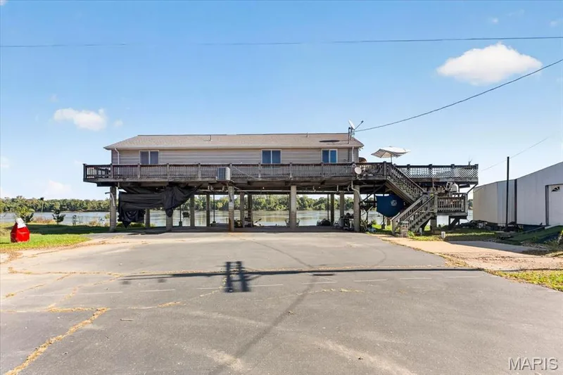 Elevated waterfront structure featuring horizontal siding, a wrap-around wooden deck, and an external staircase — 69 Weule Boat Harbor, St Charles, MO 63301