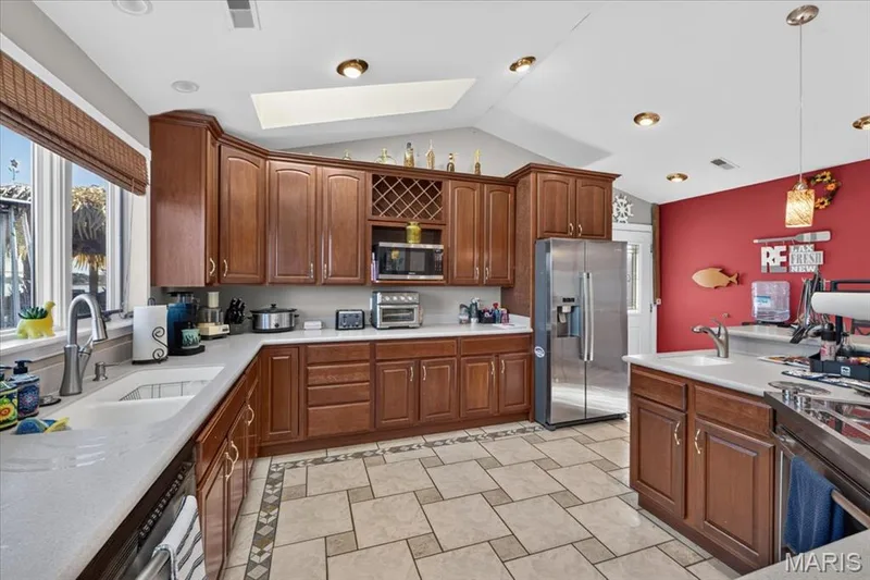 Kitchen featuring wood cabinetry, integrated wine rack, solid-surface countertops, skylight, and tile flooring with decorative inlay — 69 Weule Boat Harbor, St Charles, MO 63301