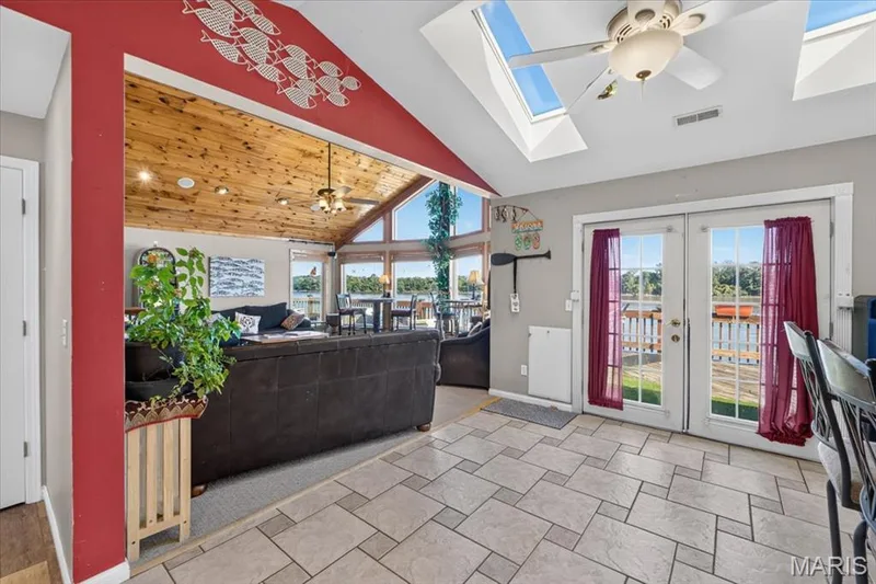 Vaulted ceiling with exposed wood planking, dual skylights, full-wall windows, and dual glass-paned doors leading to exterior decking — 69 Weule Boat Harbor, St Charles, MO 63301