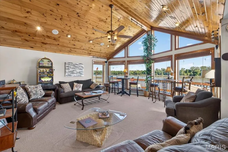Vaulted ceilings featuring natural wood-finish paneling, expansive floor-to-ceiling windows, integrated ceiling fan, and carpeted flooring — 69 Weule Boat Harbor, St Charles, MO 63301