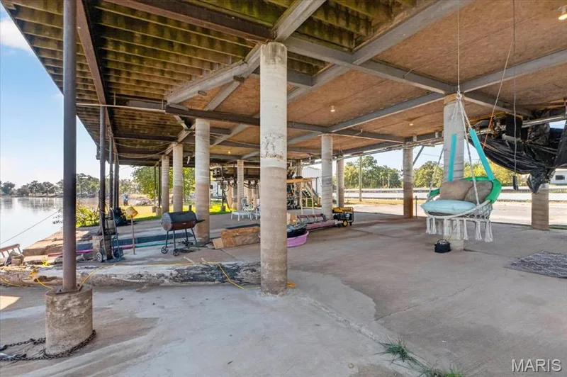 Covered ground-level patio featuring a concrete floor, structural steel framing, exposed timber joists, and concrete support columns — 69 Weule Boat Harbor, St Charles, MO 63301