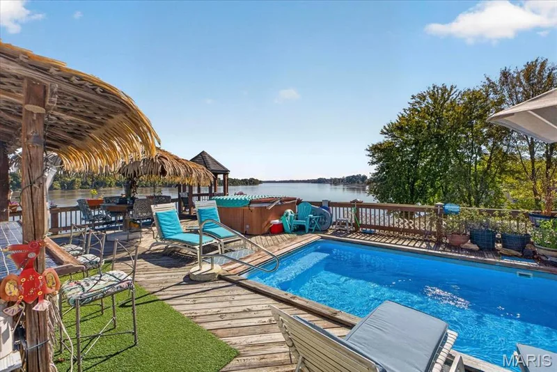 Elevated wooden deck featuring an in-ground swimming pool, a built-in hot tub, perimeter railing, and direct water frontage — 69 Weule Boat Harbor, St Charles, MO 63301