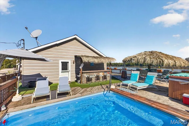 Outdoor deck featuring a swimming pool, integrated hot tub, and a built-in bar with thatched-style roofing — 69 Weule Boat Harbor, St Charles, MO 63301