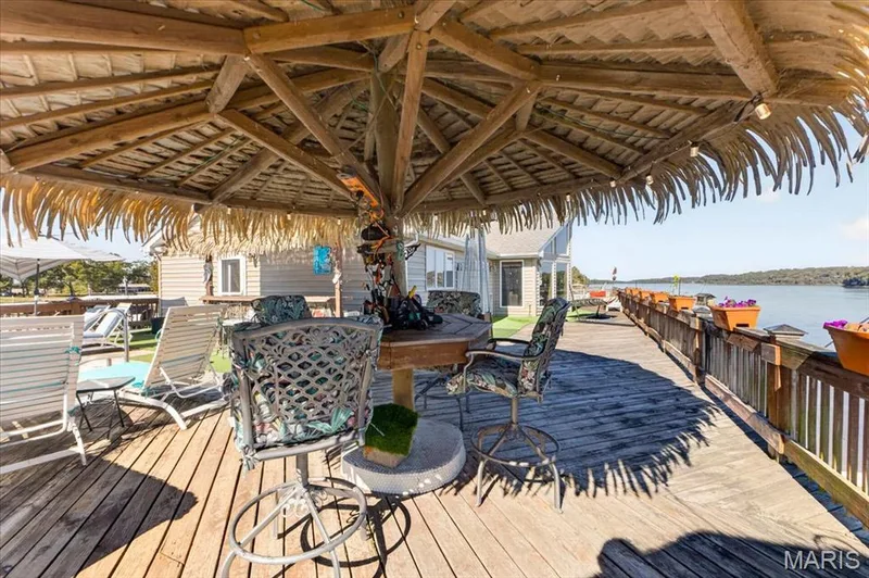 Expansive waterfront deck featuring natural wood decking, a permanent tiki-style thatched roof structure, and perimeter railing with integrated planter boxes — 69 Weule Boat Harbor, St Charles, MO 63301
