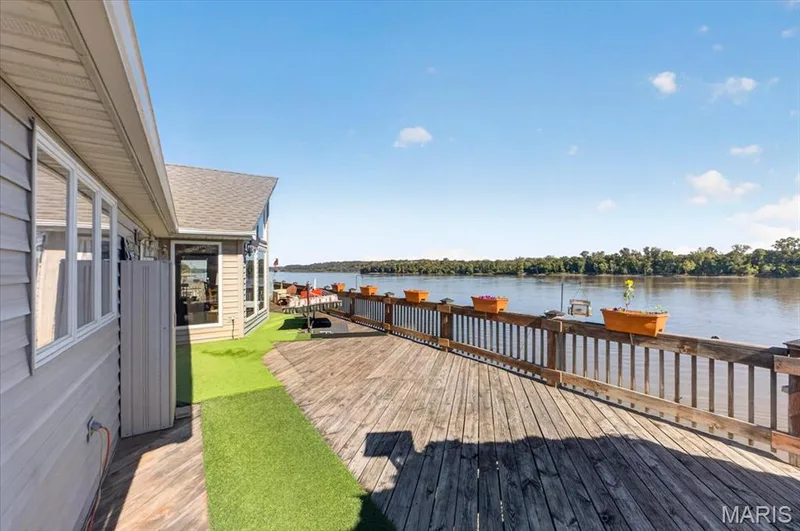 Expansive wood deck with a protective railing, integrated green synthetic turf surfacing, and water frontage — 69 Weule Boat Harbor, St Charles, MO 63301