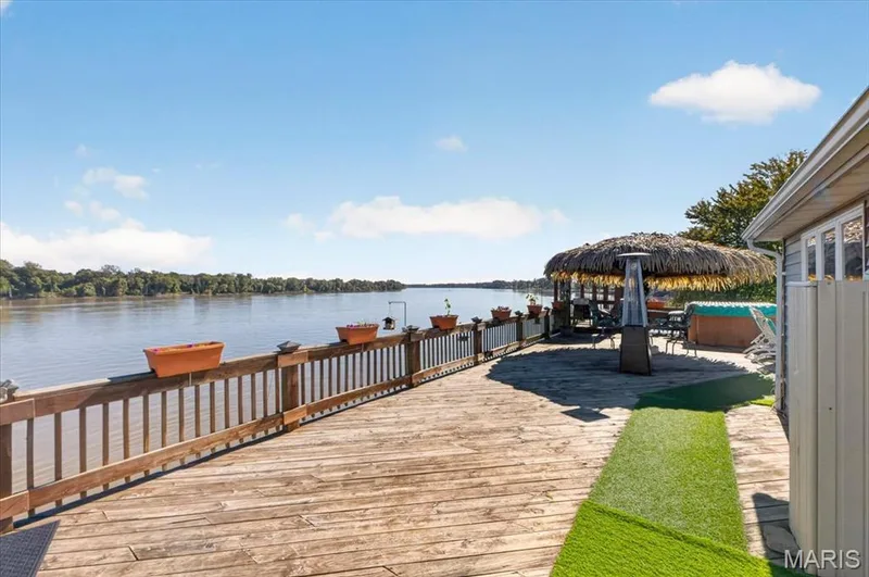 Expansive wood deck featuring a balustrade railing, integrated hot tub, and direct water frontage — 69 Weule Boat Harbor, St Charles, MO 63301