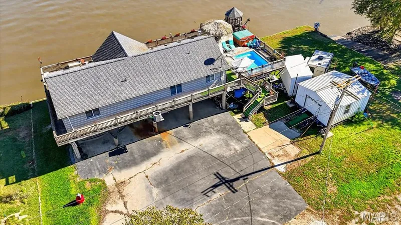 Waterfront property featuring an elevated deck, an in-ground pool, and a detached structure on a paved lot — 69 Weule Boat Harbor, St Charles, MO 63301