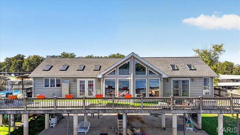 Waterfront residence featuring horizontal siding, expansive windows, multiple skylights, and an elevated wrap-around deck — 69 Weule Boat Harbor, St Charles, MO 63301