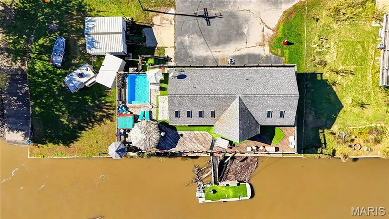 Aerial view of a waterfront property featuring a swimming pool, expansive multi-level wood decking, roof-integrated skylights, and a private dock — 69 Weule Boat Harbor, St Charles, MO 63301