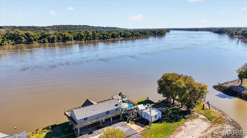 Waterfront property featuring an elevated structure, expansive deck, detached storage building, and direct water access — 69 Weule Boat Harbor, St Charles, MO 63301
