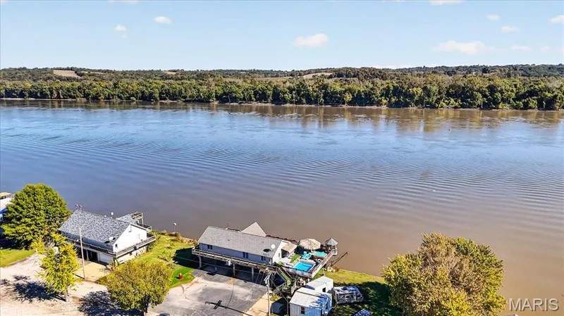 Waterfront property featuring extensive river frontage, a built-in swimming pool, paved driveway, and mature landscaping — 69 Weule Boat Harbor, St Charles, MO 63301