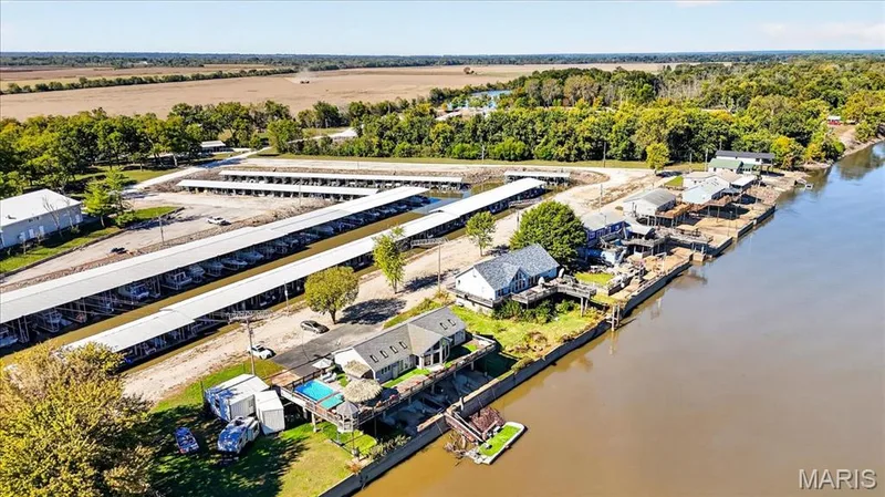 Waterfront property featuring extensive covered boat slip infrastructure, an in-ground swimming pool, raised wooden decking, and direct water access — 69 Weule Boat Harbor, St Charles, MO 63301