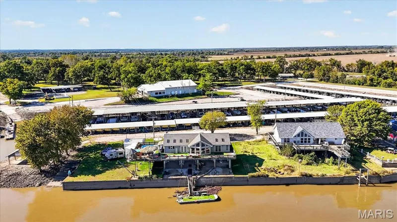 Waterfront estate featuring a concrete bulkhead, private boat dock, elevated rear decking, and covered boat slip storage — 69 Weule Boat Harbor, St Charles, MO 63301