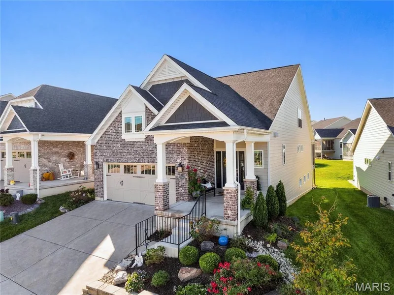 Exterior facade featuring brick masonry, horizontal siding, gabled rooflines, and a covered front porch with tapered columns — 17028 Fire Glow Drive, Wildwood, MO 63011