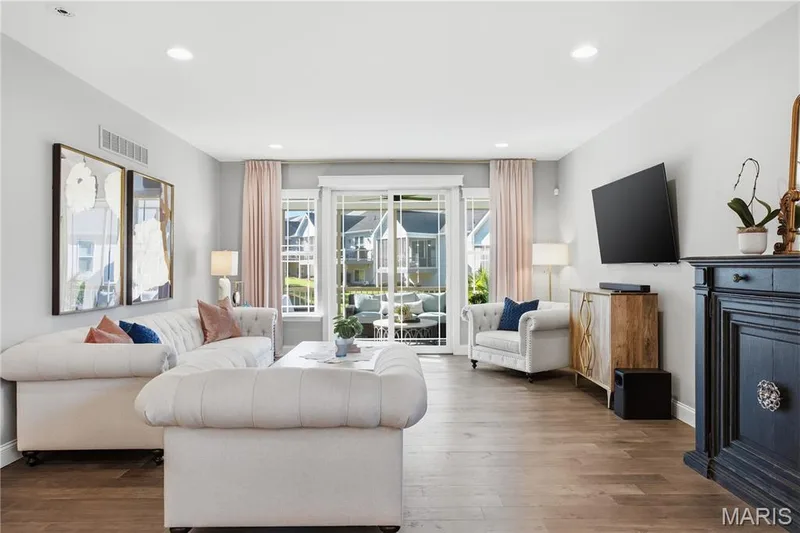 Wood-finish flooring, recessed lighting, and sliding glass doors featuring muntin bars, complemented by a built-in dark-toned cabinet with decorative hardware — 17028 Fire Glow Drive, Wildwood, MO 63011