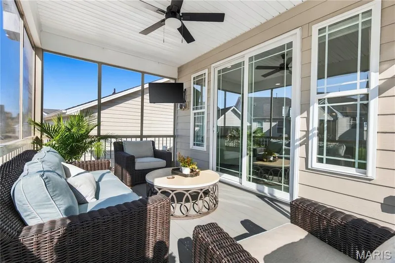Screened-in porch featuring gray composite decking, horizontal lap siding, sliding glass doors, and a ceiling fan — 17028 Fire Glow Drive, Wildwood, MO 63011