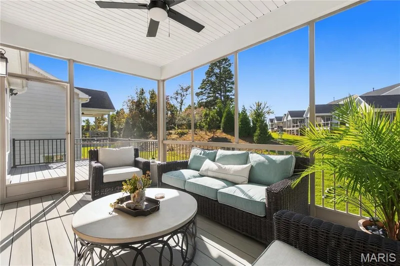 Screened porch featuring light-toned composite decking, a white beadboard ceiling, a central ceiling fan, and metal railings — 17028 Fire Glow Drive, Wildwood, MO 63011