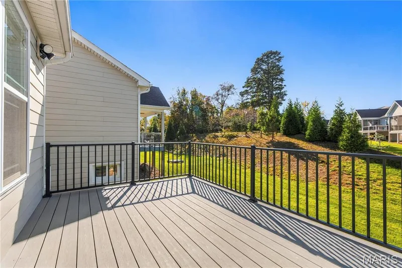 Elevated composite deck featuring black metal railing, neutral-toned planking, and siding exterior — 17028 Fire Glow Drive, Wildwood, MO 63011