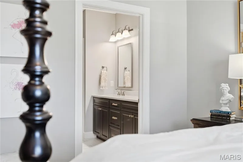 Bathroom featuring a vanity with dark cabinetry, stone-finish countertop, three-light fixture, and rectangular mirror — 17028 Fire Glow Drive, Wildwood, MO 63011